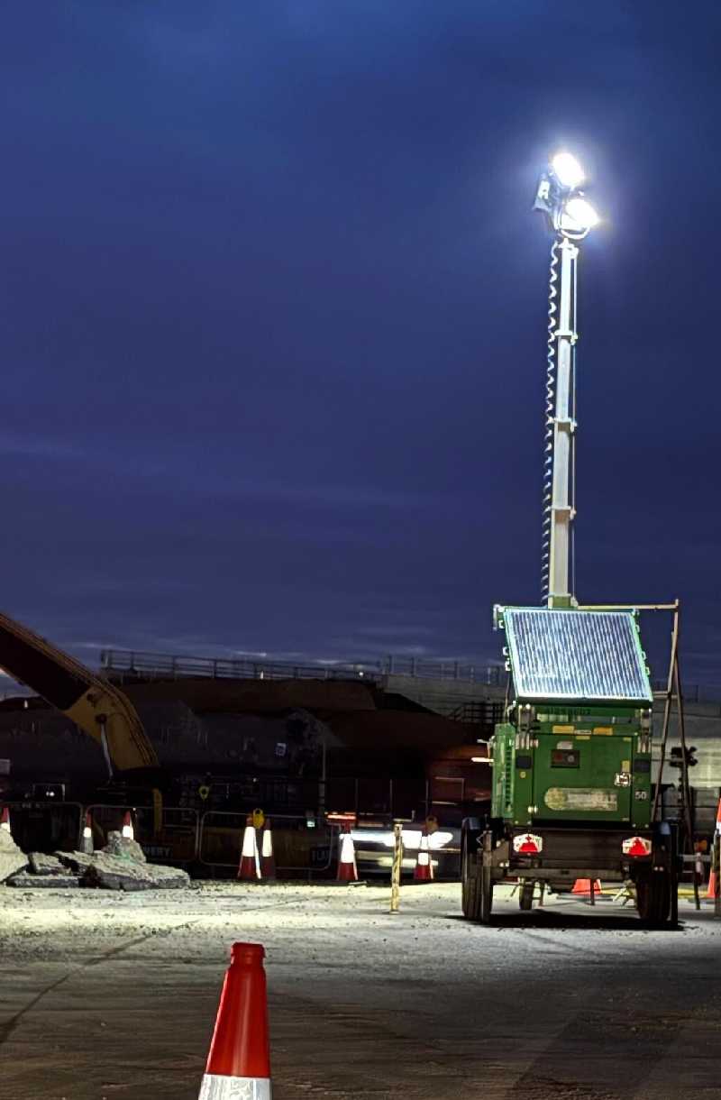 a trime solar hybrid lighting tower with solar panel lithium batteries and diesel engine providing light in a construction site